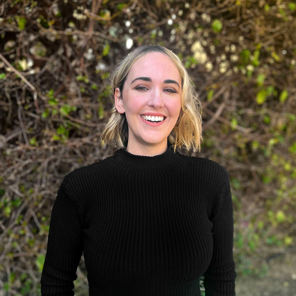 Holistic anxiety & attachment therapist in Los Angeles. Photo shows Cheryl Groskopf, a therapist in LA and Pasadena, smiling in front of green bushes. Therapist in smiling and engaging.