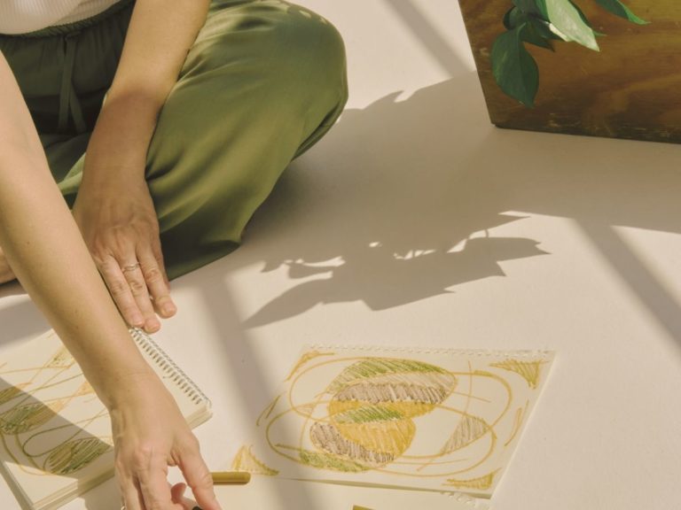 Person sitting on the floor, drawing with focus and calm during a somatic therapy session in Los Angeles