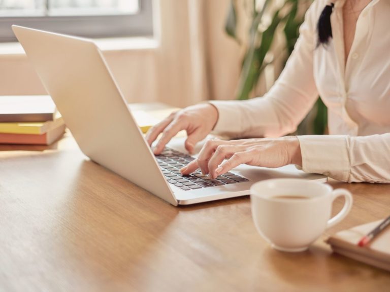 Person in Los Angeles on their laptop, searching for an anxiety therapisti n Los Angeles. Photo shows white laptop and hands on a wooden table.