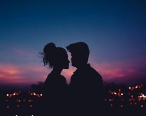 Couple in los angeles cuddling in front of the los angeles sunset; sunset is purple. Couple looks happy. Photo highlighting fearful avoidant attachment therapy in Los Angeles