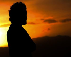 Man in Los Angeles standing in front of sunset. Photo is man's shadow and orange sunset. Photo for attachment therapy in los angeles for fearful avoidant attachment.