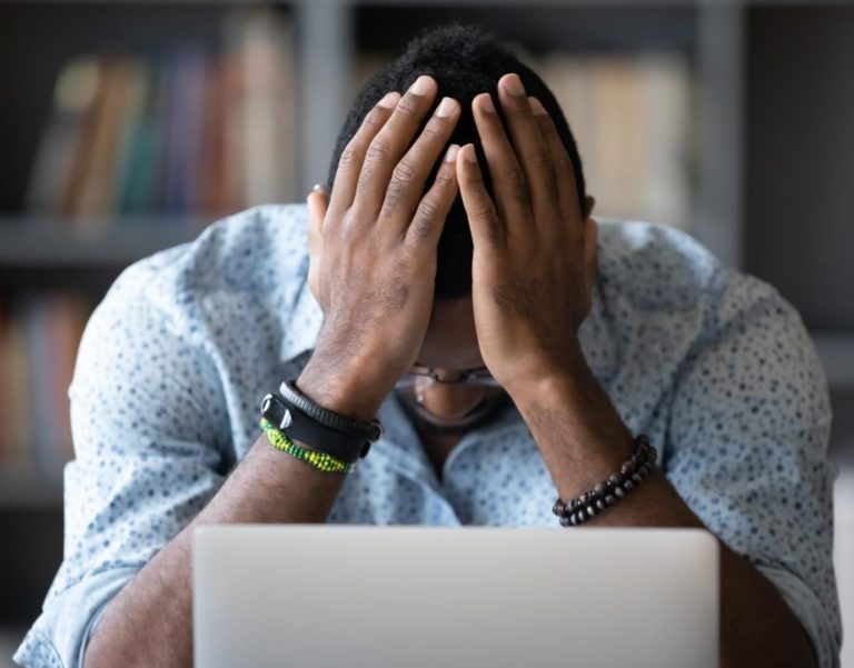 Man looking stressed out on the computer. Man is doing online trauma therapy in Los Angeles and looks like he's sharing feelings.