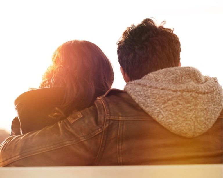 Photo of a couple hugging each other in therapy in Los Angeles. Photo shows the couple's backs, and both are wearing tan jackets. couple looks securely attached to one another.