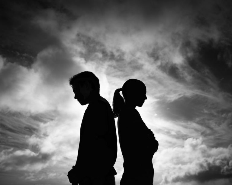 Photo of a couple in Los Angeles. The couple is standing away from each other and their body language looks like they are fearful avoidant attachment. Photo is black and white