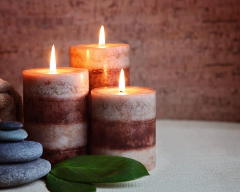 An attachment and anxiety therapy office in Los Angeles. 3 candles are lit and there are two stones on the table. background is brick red and table is white