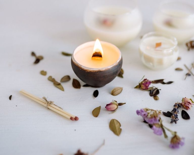 A somatic and anxiety therapy office in Los Angeles. A single candle is lit and two unlit in back. The table is white.