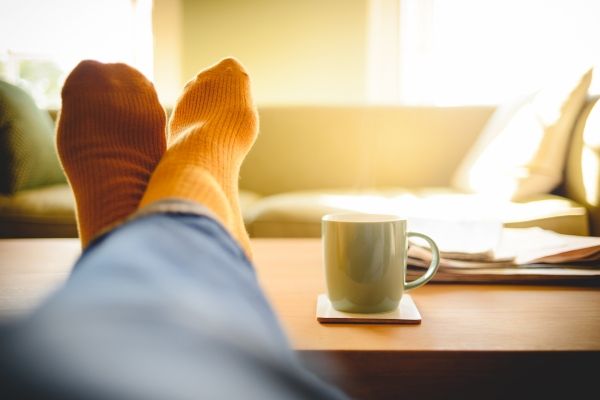 Client experiencing relaxation in somatic therapy session, Los Angeles, with feet on table and orange socks.