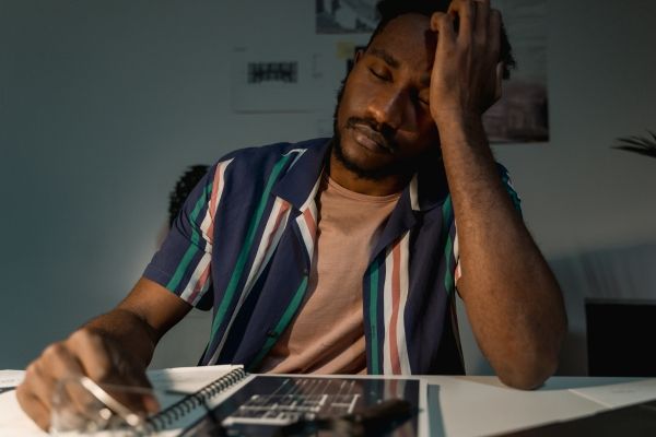 Person journaling inside a room in Los Angeles. Man looks tired and frustrated