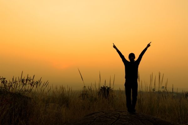 Individual stands outside with their arms up during a Los Angeles Sunset.