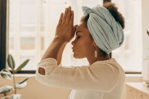 Woman practicing somatic therapy in a prayer position overhead in a Los Angeles therapy office