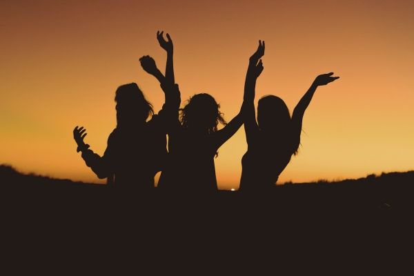 Shadows of 3 women jumping with arms up against an LA sunset