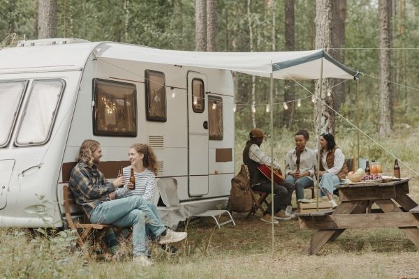 group of people in their 20s and 30s camping in a cute RV, smiling and enjoying their time. Anxiety therapy Los Angeles and people-pleasing therapy Los Angeles