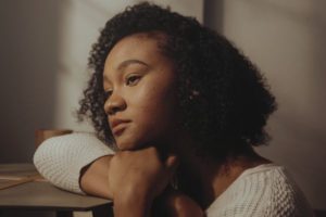 A woman looking off, appearing sad and exhausted from people-pleasing. Anxiety therapy Los Angeles and people-pleasing therapy Los Angeles.