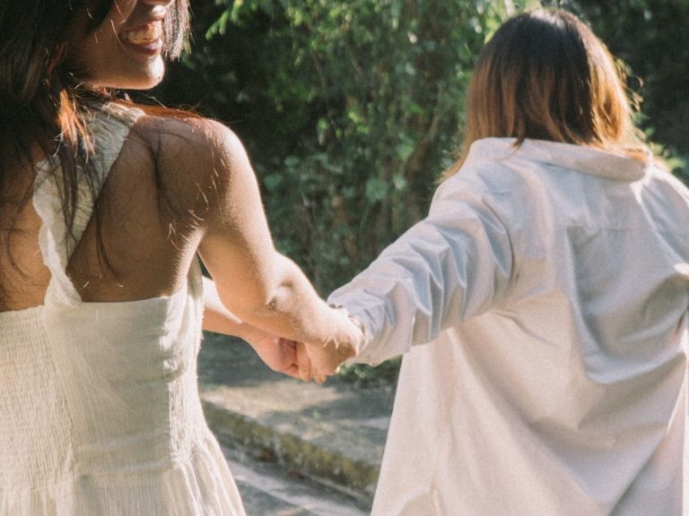 Close-up of two women holding hands during a supportive somatic therapy session in Los Angeles, emphasizing connection and healing