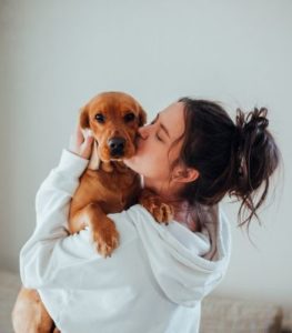 Girl holding a dog and kissing it's cheek, symbolizing emotional connection and healing through somatic therapy in Los Angeles for childhood trauma