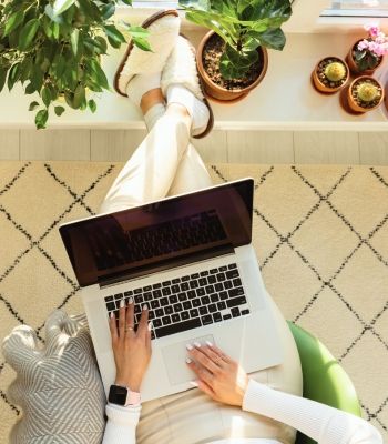 Woman doing online therapy in California to treat her anxiety. Photo shows laptop, a female's legs and hands typing with tile under her feet in Los Angeles apartment.