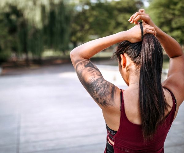 Woman in los angeles walking home from a somatic therapy session. Woman is putting her hair up and wearing workout clothes