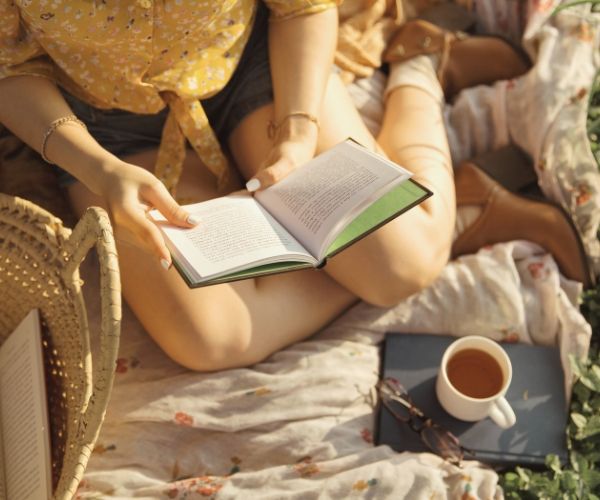 Person sitting down and reading a book about IFS therapy in Los Angeles, showing their legs and book.