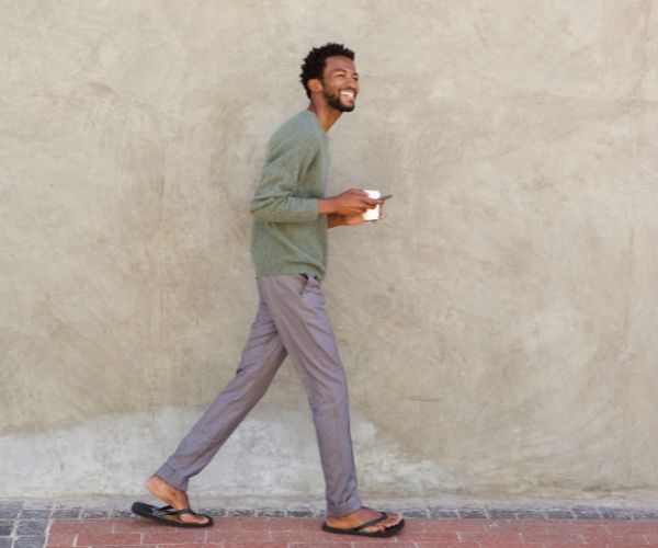 Smiling man walking with coffee, representing mindfulness and movement in somatic therapy Los Angeles