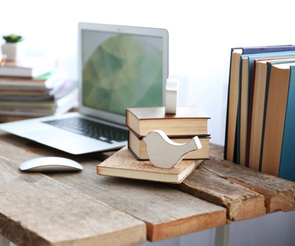 Wooden desk setup with books, a laptop, and a decorative bird, symbolizing a calm and reflective space for trauma therapy in Los Angeles.