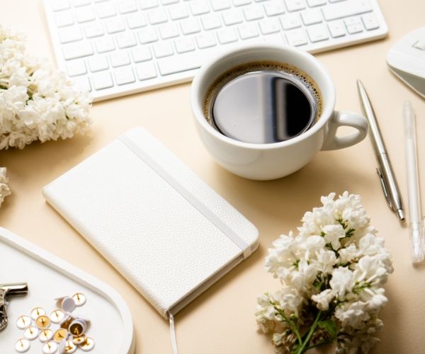 A cozy holistic workspace with a notebook, coffee, and flowers, symbolizing reflection and self-care, key elements of somatic and trauma therapy in Los Angeles.