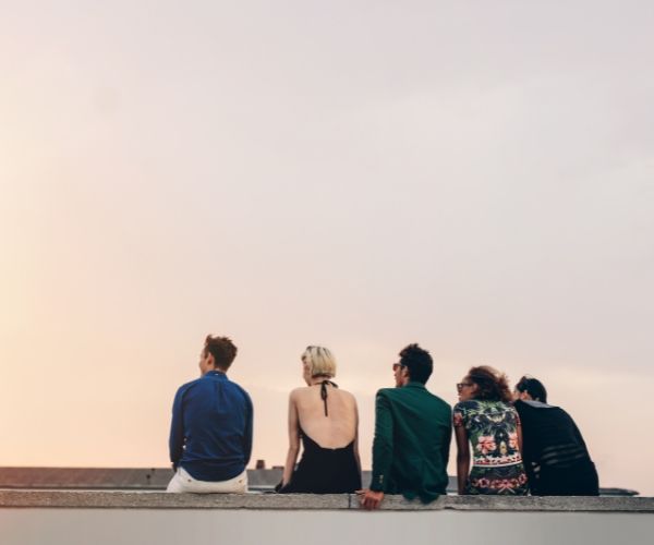 A group of people sitting on a rooftop at sunset, reflecting mindfulness and self-awareness, key components of somatic and trauma therapy in Los Angeles.