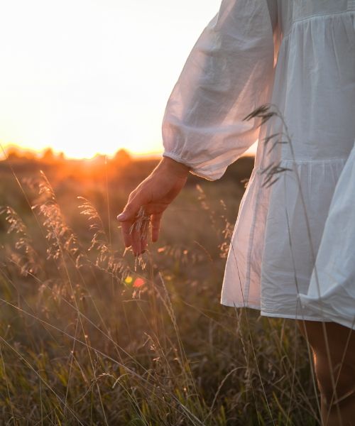 Person walking across a field with grass, representing relaxation and nervous system regulation through somatic trauma therapy in Los Angeles.