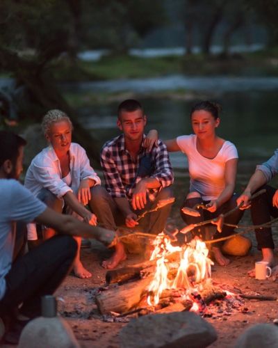 A group of people gathered around a bonfire at Dockweiler State Beach in Los Angeles, symbolizing connection, warmth, and the power of co-regulation in trauma healing.