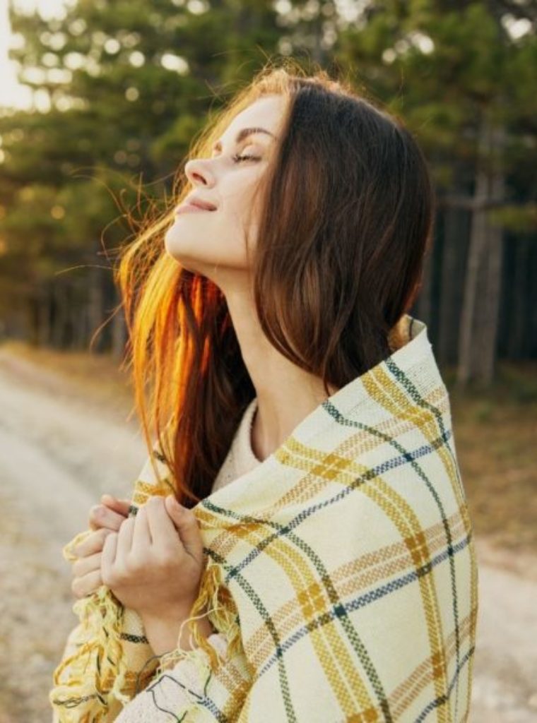 woman seeking trauma therapy in los angeles. outside, blanket wrapped around her, brown hair