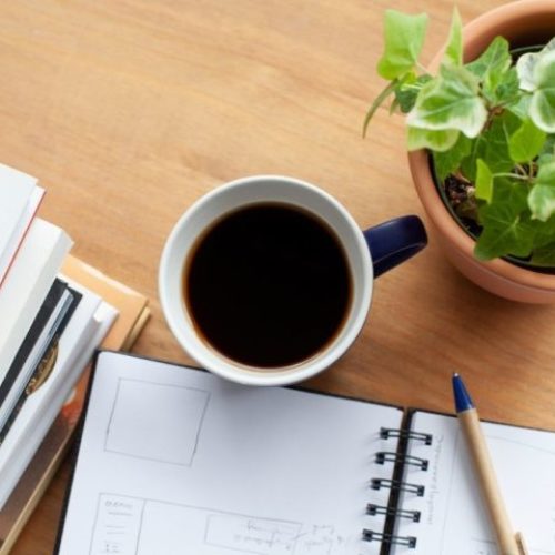 An attachment and holistic therapy office in Los Angeles. A cup of coffee, blank journal, books and a pen are on the wooden table