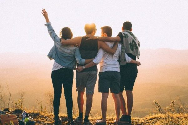 Group of friends in Los Angeles looking out towards sunset. 4 friends with back towards camera and holding each other after attachment therapy