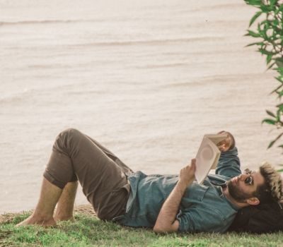 Man reading a book near a lake in Los Angeles, reflecting on personal growth and healing through therapy.