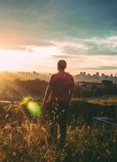 Man walking in Los Angeles. Los Angeles mountains in background and blue sky. Man is facing away from the camera