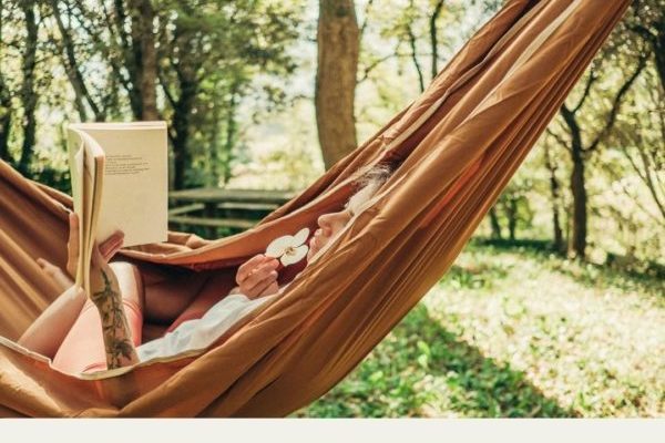 Person reading book on a hammock with relaxing Los Angeles background. Photo represents IFS therapy in Los Angeles for harmony