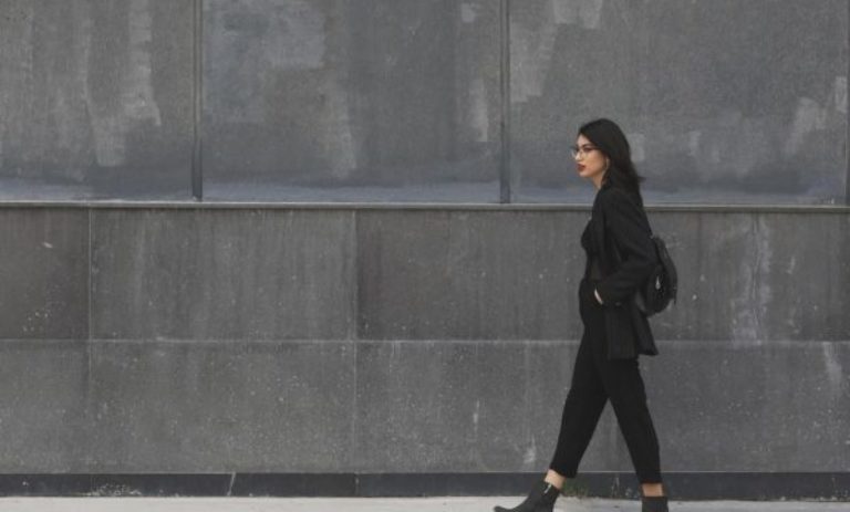 Woman wondering what to expect in therapy in Los Angeles. Woman wearing all black walking to therapy on a Los Angeles street. Background is gray.